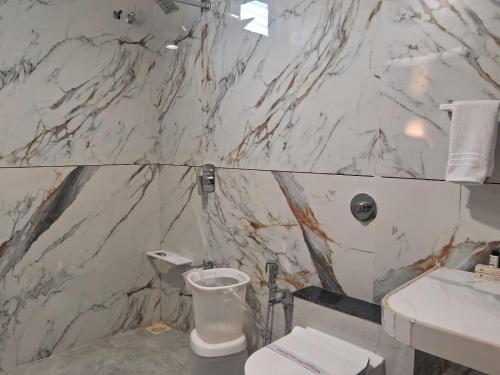 a marble bathroom with a toilet and a sink at KING'SWAY Hotel & Resort in Dūngarpur