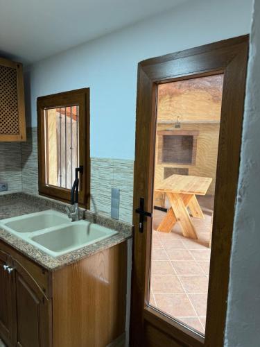 La Campanilla في Los Corrales: مطبخ مع حوض وباب زجاجي منزلق