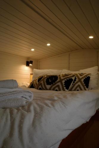 a bed with white sheets and pillows in a room at Natura Tiny House in Mărişel