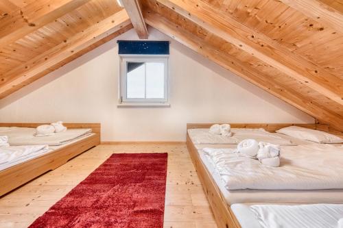 Cette chambre mansardée comprend 2 lits et un tapis rouge. dans l'établissement Panorama Ferienhaus Zora, à Gurtis