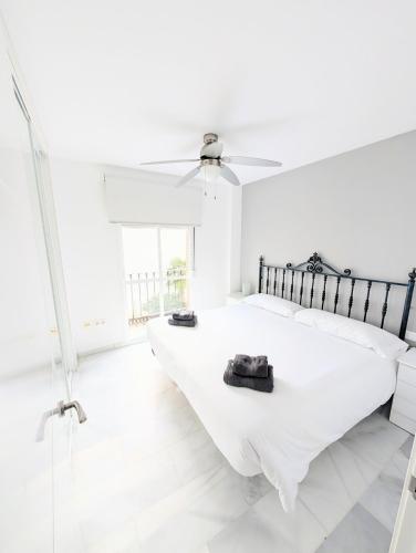a white bedroom with two beds and a ceiling fan at Laguna Beach 15 Primera linea de Playa in Morche