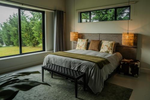 a bedroom with a bed and two windows at Kalm - Riverside living in Malgas