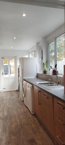 a kitchen with a white refrigerator and a dishwasher at Cheltenham town centre with parking space in Cheltenham
