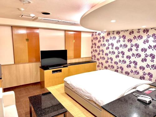 Un dormitorio con una cama y un televisor de pantalla plana. en ホテル ルヴワール, en Izumi