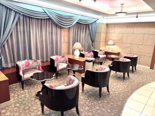 una sala de espera con sillas, mesas y cortinas en ホテル ルヴワール, en Izumi