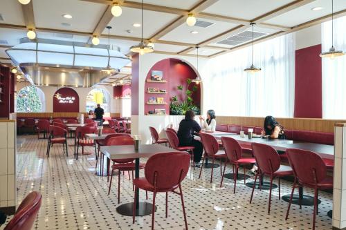 a restaurant with red chairs and tables and people sitting at tables at GO Hotel Bangkok Suvarnabhumi Airport in Lat Krabang