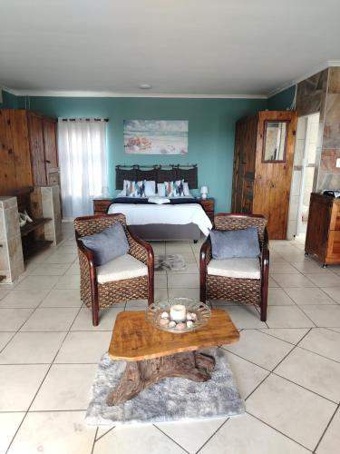 ein Schlafzimmer mit einem Bett, zwei Stühlen und einem Tisch in der Unterkunft Ocean Nook in Gqeberha