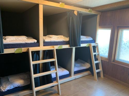 a room with four bunk beds in it at 釧路の夕日に近い宿トラベラーズイン南大通 in Kushiro