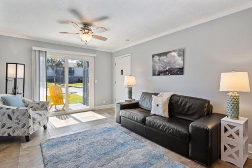 a living room with a black leather couch and a ceiling fan at Tranquil Beach Retreat - Fernandina Shores 6398 in Fernandina Beach