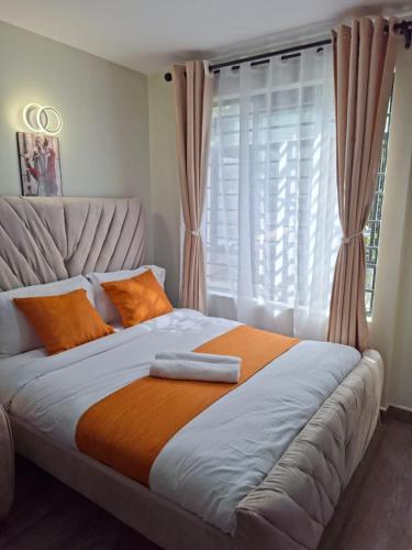 ein Bett mit einer orangefarbenen Decke und einem Fenster in der Unterkunft Staycation with Ryn in Ruaka