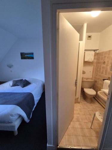 a room with a bed and a bathroom with a toilet at La Roche du Marais in Omonville-la-Petite