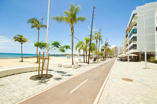 una strada con palme sulla spiaggia di Kendall Luxury ad Arrecife