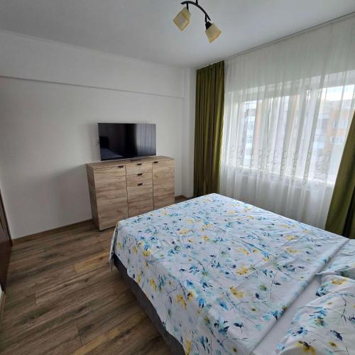 a bedroom with a bed and a dresser with a television at Downtown City Apartment in Râmnicu Vâlcea