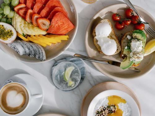 una mesa con tres platos de comida y una taza de café en Elysium Noosa Resort - MGallery Collection, en Noosa Heads
