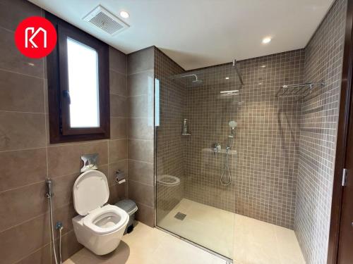 Un baño con inodoro y ducha con puerta de cristal. en Luxurious Golf and Sea View 2 Bedroom Apartment, en As Sīfah