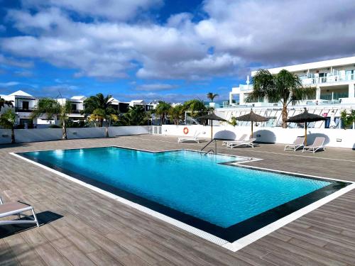 ein Swimmingpool mit Stühlen und Sonnenschirmen neben einem Gebäude in der Unterkunft Luxury Senator Apartments in Costa Teguise