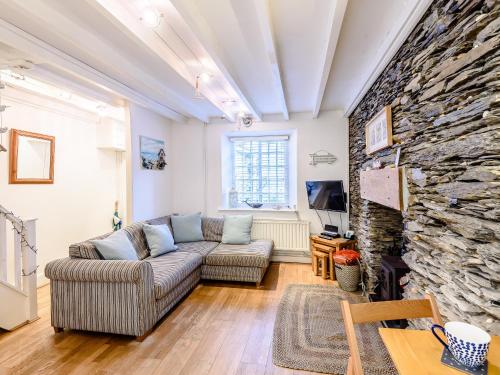 een woonkamer met een bank en een stenen muur bij Pebble Cottage - Uk32243 in Aberdyfi