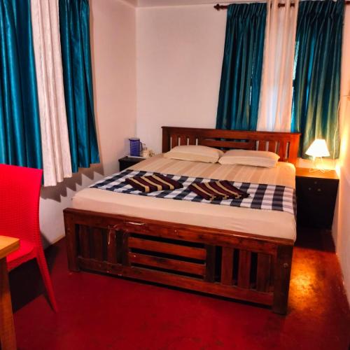 a bedroom with a wooden bed with blue curtains at Perch Next door in Kannur