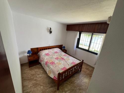 een kleine slaapkamer met een bed en een raam bij Chalet del Sur in Villa Gesell