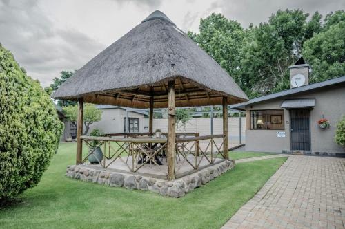 un cenador con techo de paja en un patio en Summer House, en Harrismith