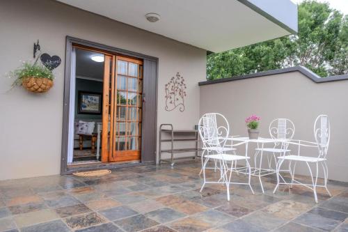 un patio con sillas blancas y una mesa en Summer House, en Harrismith