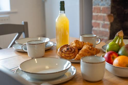 a table with plates of food and a bottle of orange juice at Wallace Hill Cottage - Garsington Studios - Pass the Keys in Stokenchurch