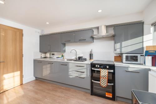 a kitchen with stainless steel appliances and gray cabinets at Wallace Hill Cottage - Garsington Studios - Pass the Keys in Stokenchurch