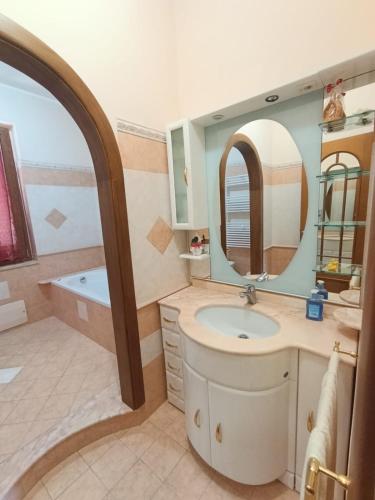 a bathroom with a sink and a tub and a mirror at PERLA VERDE Suites in Patti
