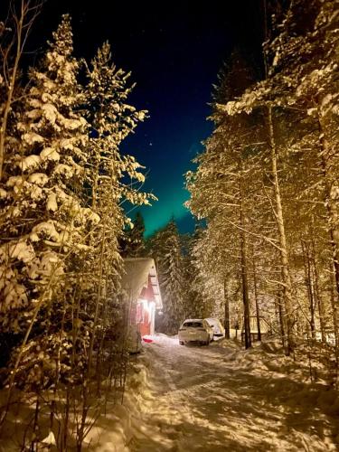 a car parked in front of a cabin in the snow at Tievaharju Cabin in Kittilä