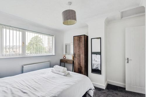 een witte slaapkamer met een bed en een spiegel bij The Escape in Swindon