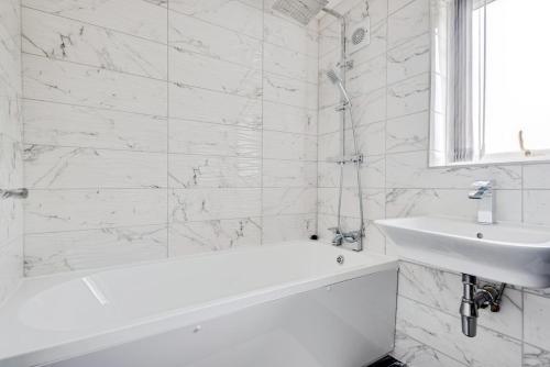 een witte badkamer met een bad en een wastafel bij The Escape in Swindon