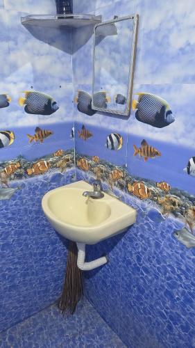 ein Badezimmer mit einem Waschbecken mit Fisch an der Wand in der Unterkunft Aravindh's Chendur HomeStay in Tiruchchendūr
