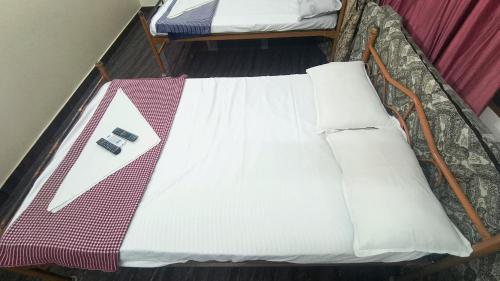 ein Bett mit einem weißen Laken und einer Fernbedienung darauf in der Unterkunft Aravindh's Chendur HomeStay in Tiruchchendūr