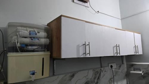 een keuken met witte kasten aan de muur bij Deoghar BnB Homestay in Deoghar