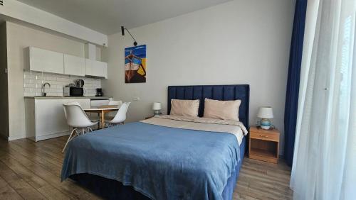 a bedroom with a bed and a table and a kitchen at Студия в White Sails видовая in Batumi