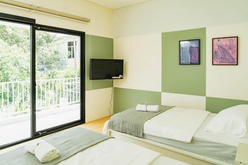 two beds in a room with a window and a tv at No303 in Bandung