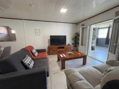 a living room with couches and a tv and a table at L'Etape du Bonheur in Cilaos