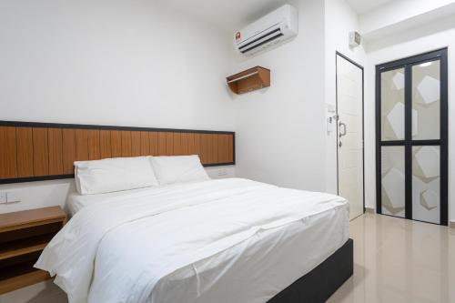 a bedroom with a white bed with a wooden headboard at TEBRAU 11 Guesthouse in Johor Bahru