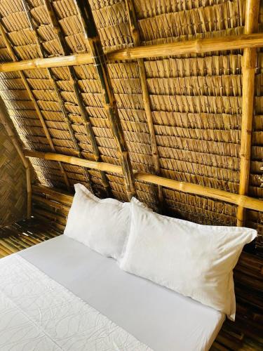 a bed in a straw hut with two pillows at Diapila baybayon Sunset View in El Nido