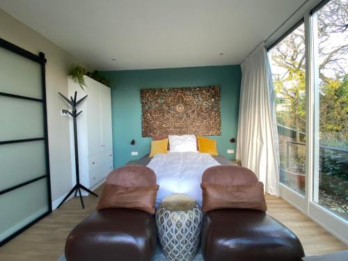 a bedroom with a bed and two chairs at Apartments Osso Arnhem in Arnhem