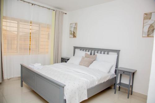 Zanube Apartments في ندولا: غرفة نوم بها سرير بملاءات بيضاء ونافذة