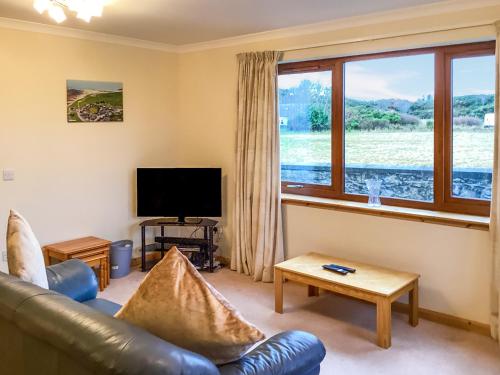 a living room with a leather couch and a television at Mirodon in Brora