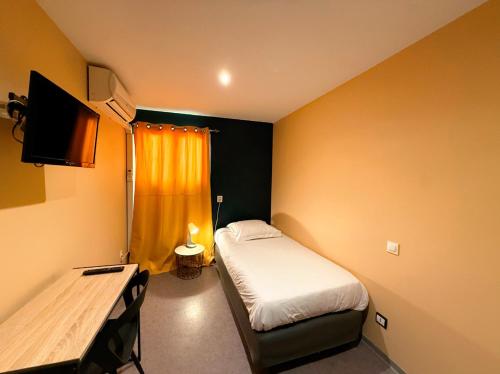 a small room with a bed and a television at Hôtel Beauséjour in Marseille