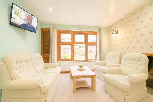 a living room with two white chairs and a tv at Ben View Guesthouse in Fort William