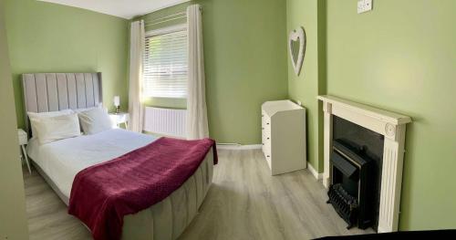 a green bedroom with a bed and a fireplace at St Columb's Cottage in Derry Londonderry