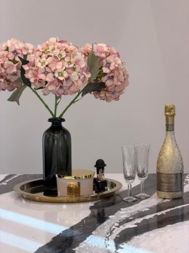 a table with a bottle of wine and a vase with flowers at Koralas in Klaipėda