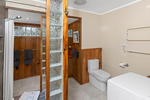 a bathroom with a toilet and a glass wall at Selwyn Cottage in Burnt Pine
