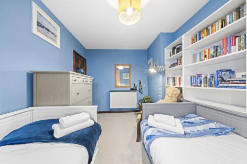 duas camas em um quarto com paredes azuis e estantes de livros em Beinn View 3 Bedroom House - Sea View - Ardersier em Ardersier