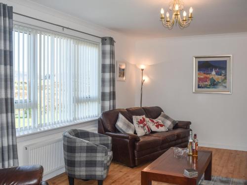 een woonkamer met een bank en een stoel bij Lochboisdale Cottage in Lochboisdale