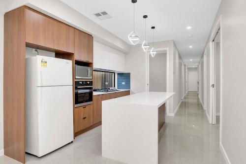 a kitchen with a white refrigerator and wooden cabinets at Luxury on Leeds #2 in Northfield